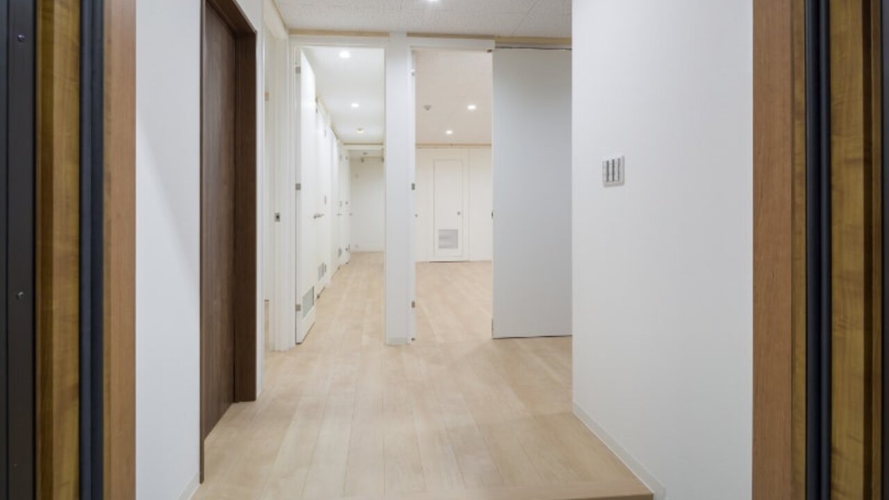 住宅環境を再現した空質空調検証室。木目のドアと白い壁が続く廊下の様子。