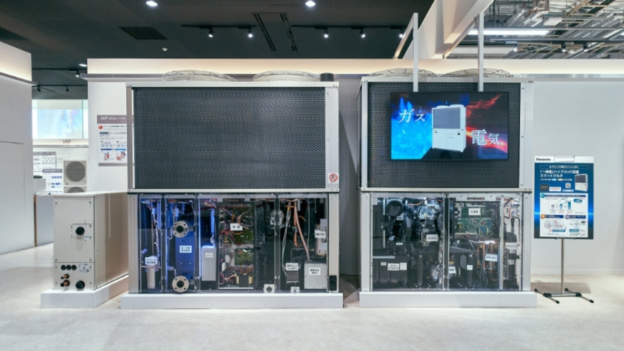 ハイブリッド空調システムの展示。大型の室外機ユニットが並び、内部構造が確認できるスケルトン仕様のモデルや解説モニターが設置されている。