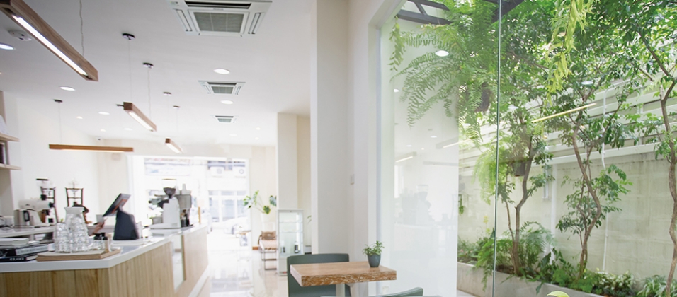 緑が見えるガラス張りのカフェの店内の画像