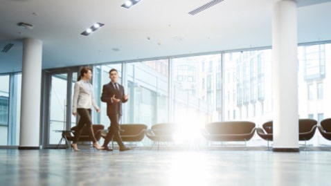 男女2人が会話をしながら社内を歩いている画像