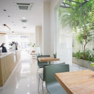 緑が見えるガラス張りのカフェの店内の画像