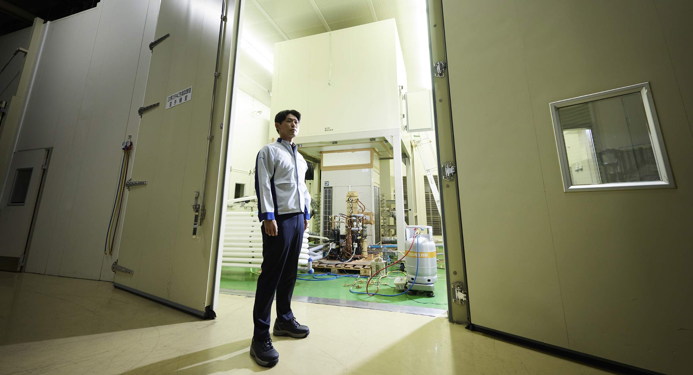 設備の大きな扉の前に佇む平池の画像