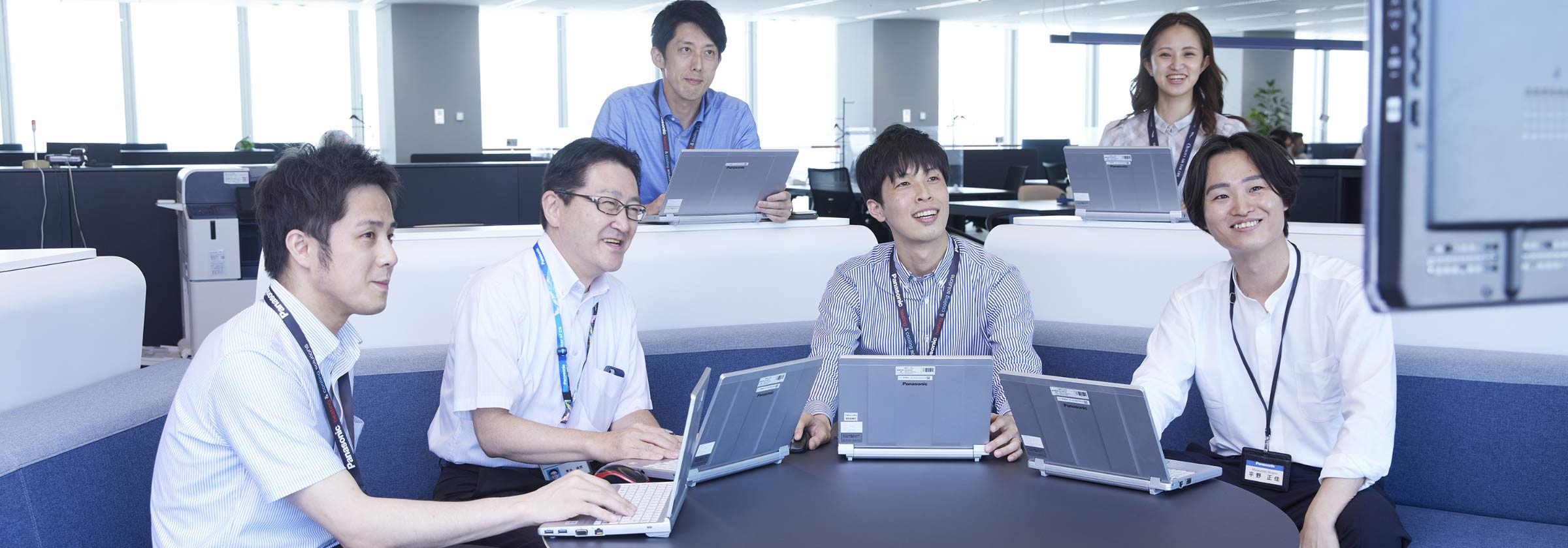 大きいモニターの前で会議をする福田と、その同僚の画像