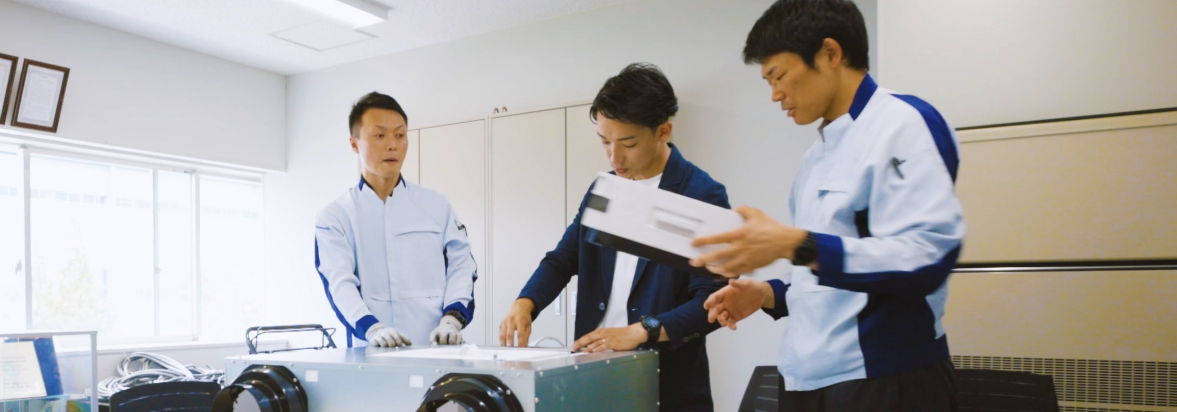 機材を囲み話し合う設備マーケティングスタッフの画像