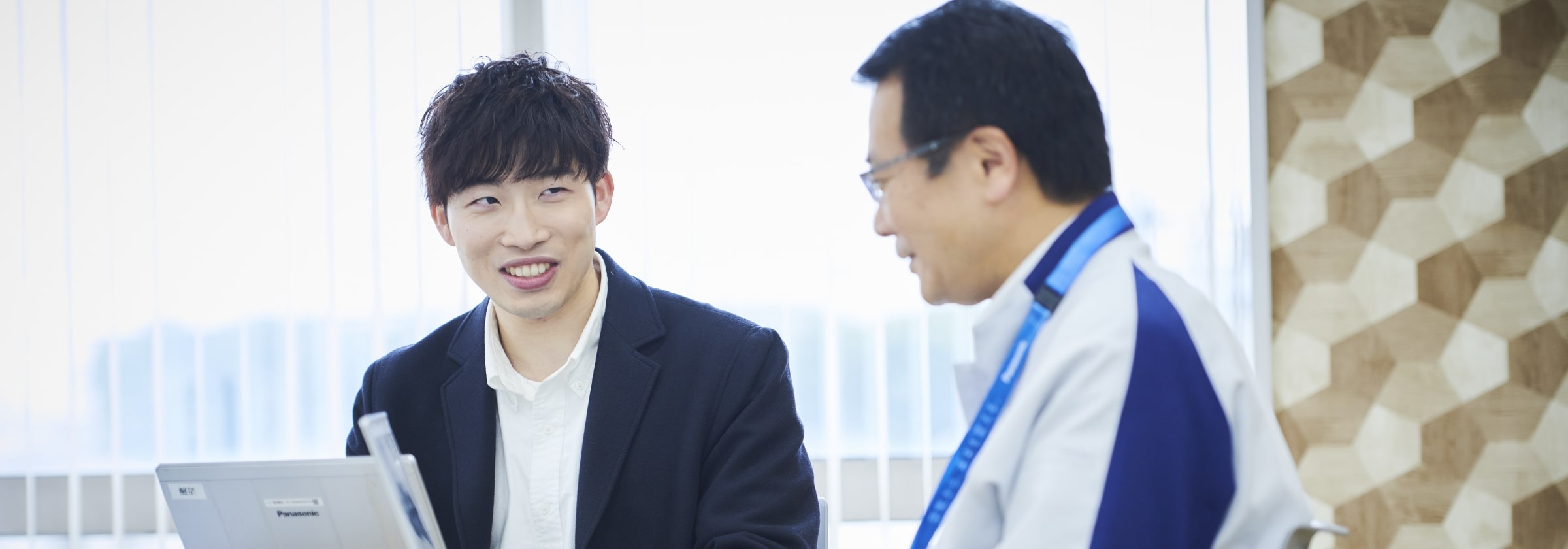 ノートパソコンを見ながら男性スタッフと話し合う設備技術スタッフの画像