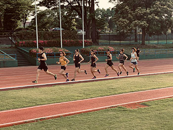 堀選手がトラックでコーチや他の選手と一緒に走る練習風景