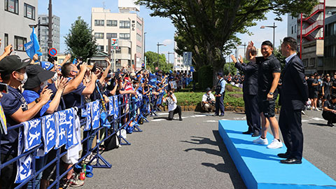 画像:沿道に設けられたお立ち台に上がり、お客様の記念撮影に笑顔で応えました。